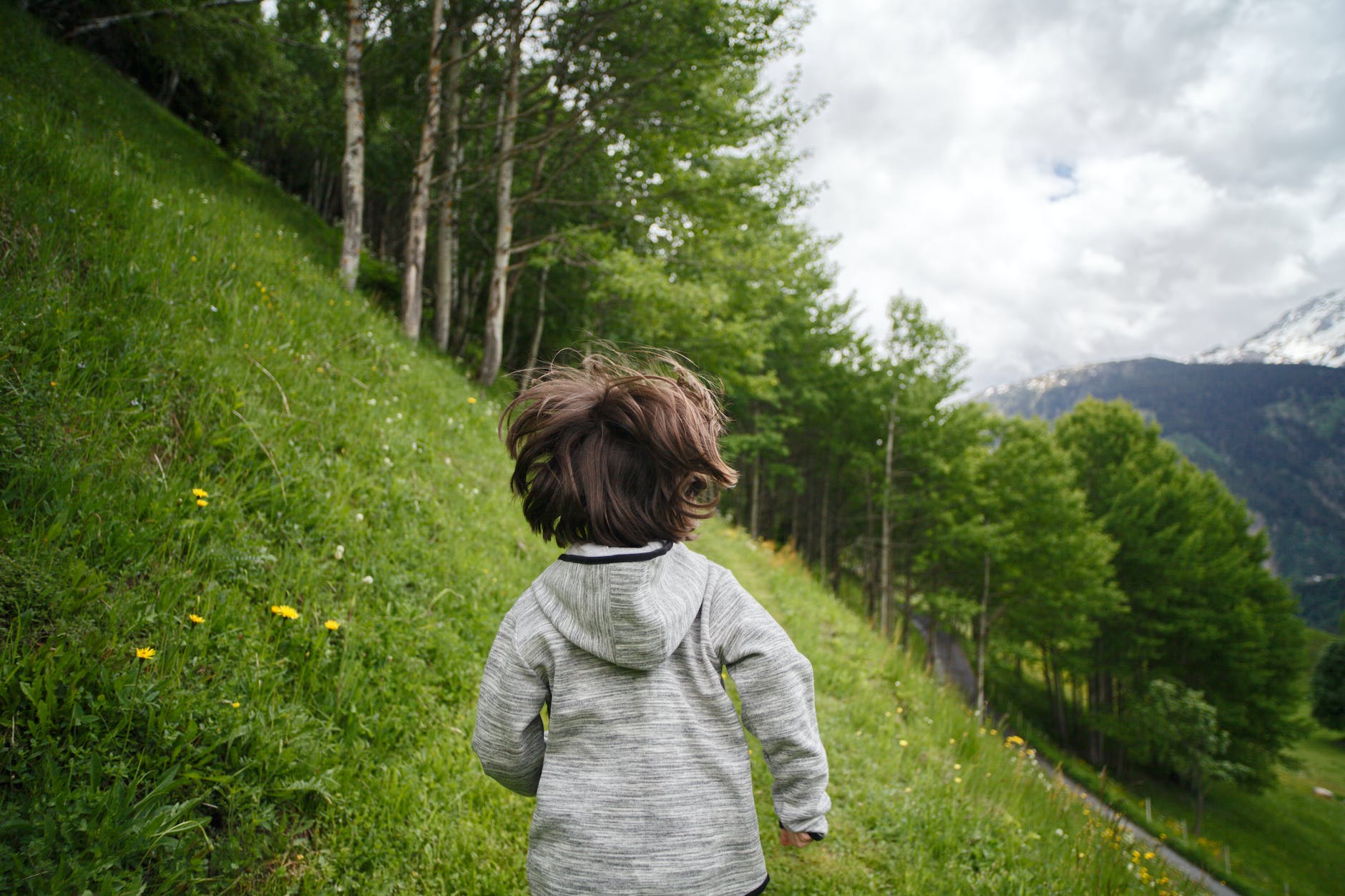 toddler wearing gray hoodie running on green fields